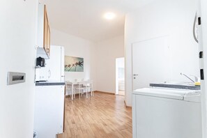 A kitchen with a dining area, a washing machine, and a door leading to another room.