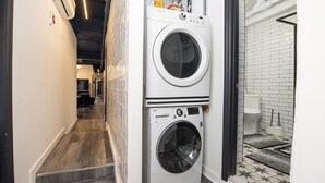 Een kleine wasruimte met een gestapelde wasmachine en droger, een zichtbaar toilet en een vloer met patroon.
