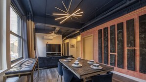 Een moderne eetruimte met een lange tafel voor zes personen, blauwe stoelen en een bijzondere wanddecoratie.