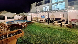 A modern two-story house with a swimming pool, outdoor seating, and a barbecue area.