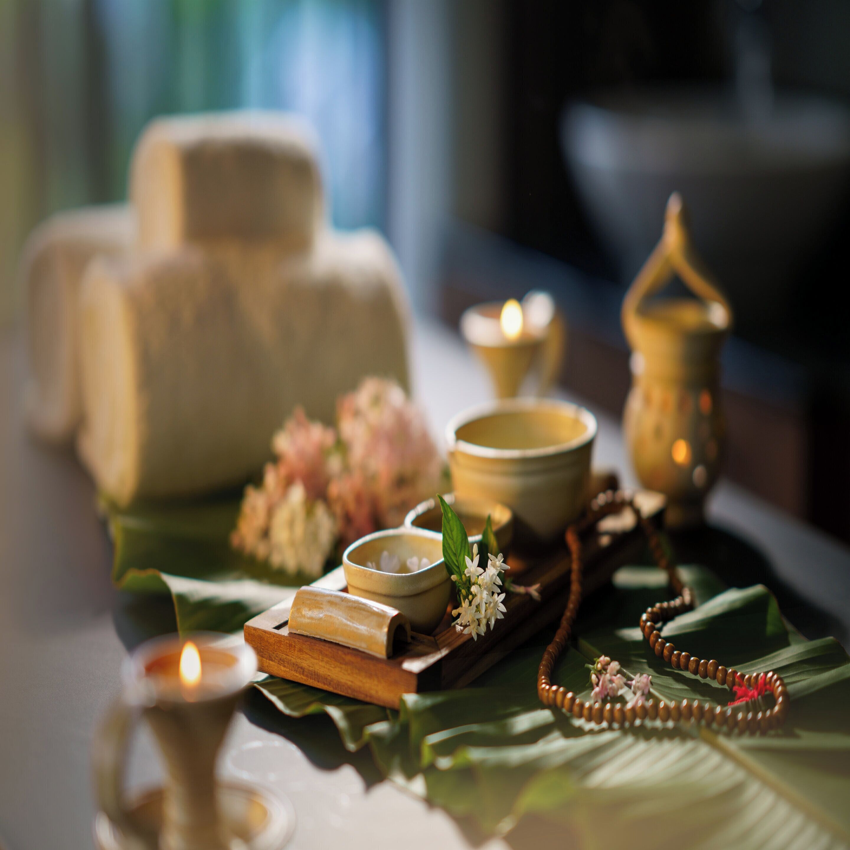A table with candles, a wooden tray, and a string of prayer beads.