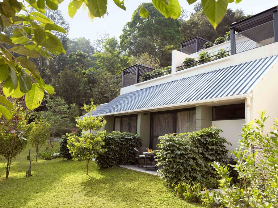 A modern house with a sloped roof, surrounded by a well-maintained garden and trees.