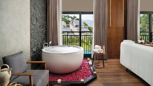 Un baño moderno con una bañera grande, un sofá y vistas a una piscina y montañas.