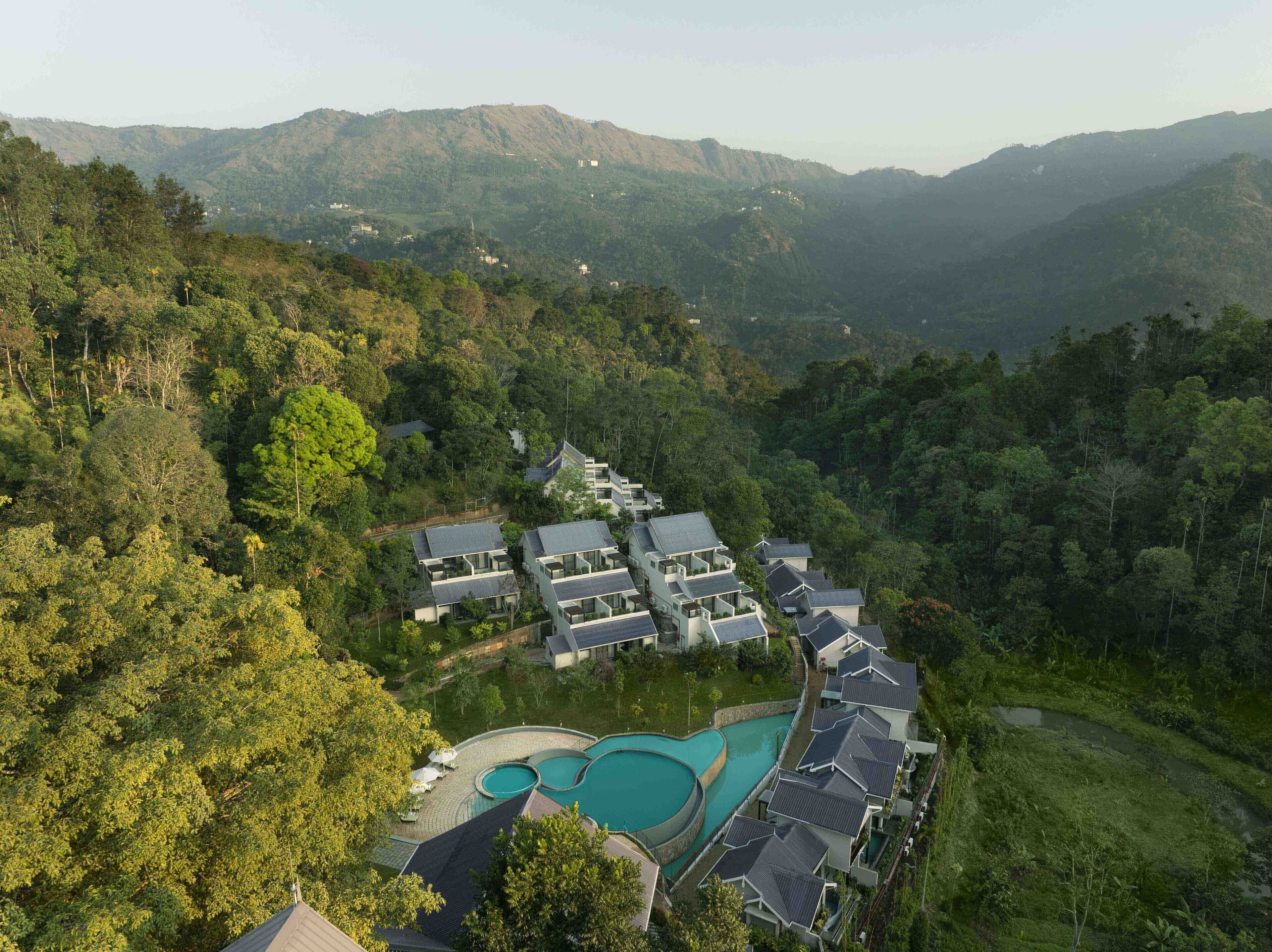 Ein Resort mit mehreren Gebäuden, einem Swimmingpool und üppigem umliegendem Wald.