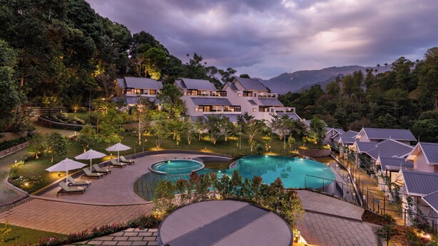 Un resort con varias construcciones, piscina y jardín paisajístico.