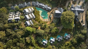Vista aérea de una zona residencial con varias casas, una piscina y vegetación circundante.