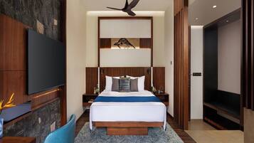 A modern hotel room with a large bed, a flat-screen TV, a wooden desk, and a ceiling fan.