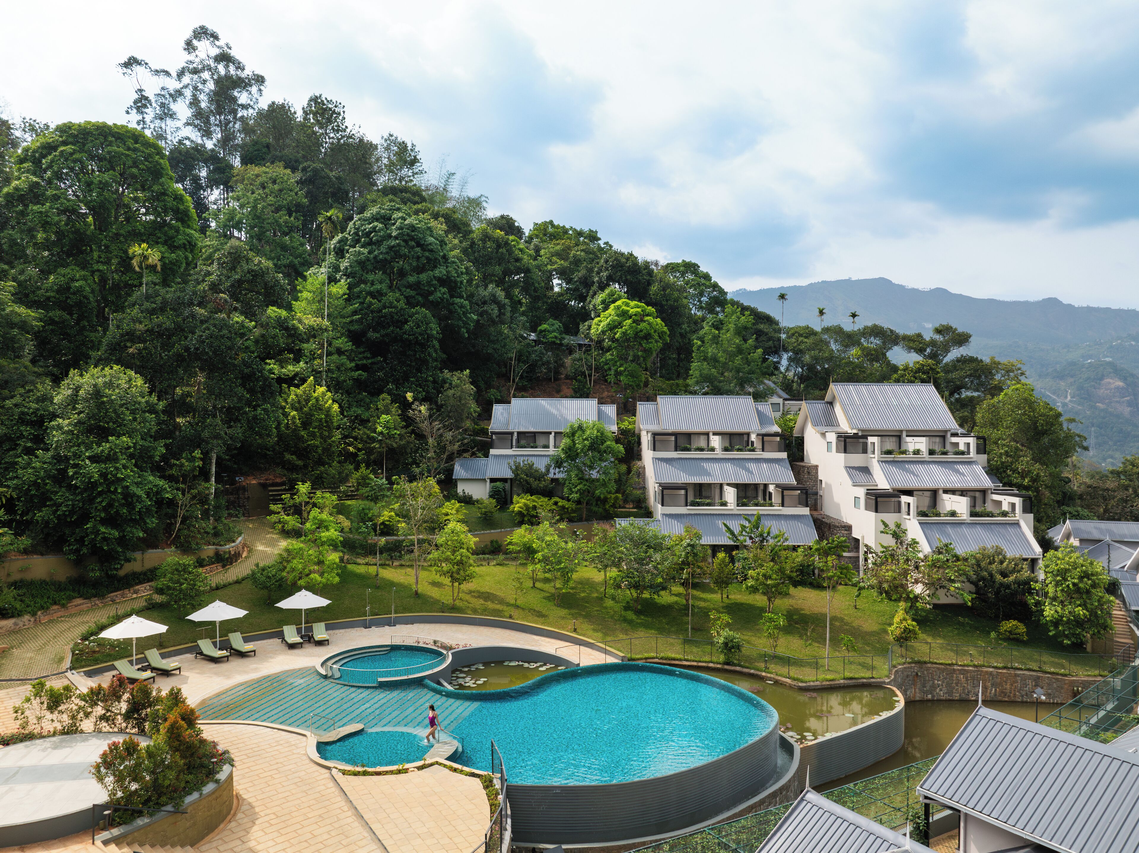A resort with multiple swimming pools, lush greenery, and modern buildings.