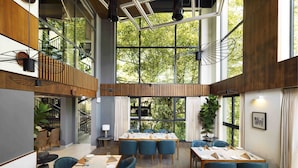 Un comedor moderno con techos altos, ventanas amplias y una mezcla de decoración de madera y metal.