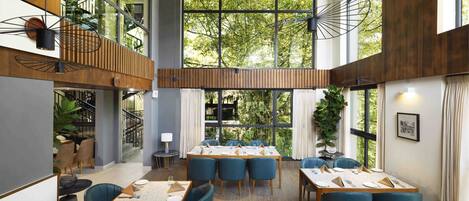 Un comedor moderno con techos altos, ventanas amplias y una mezcla de decoración de madera y metal.