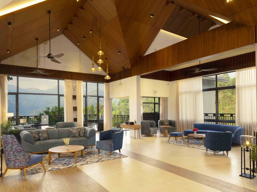Amplia sala de estar con un sofá grande, sillones y una mesa de centro, con ventanas amplias y vistas a montañas.