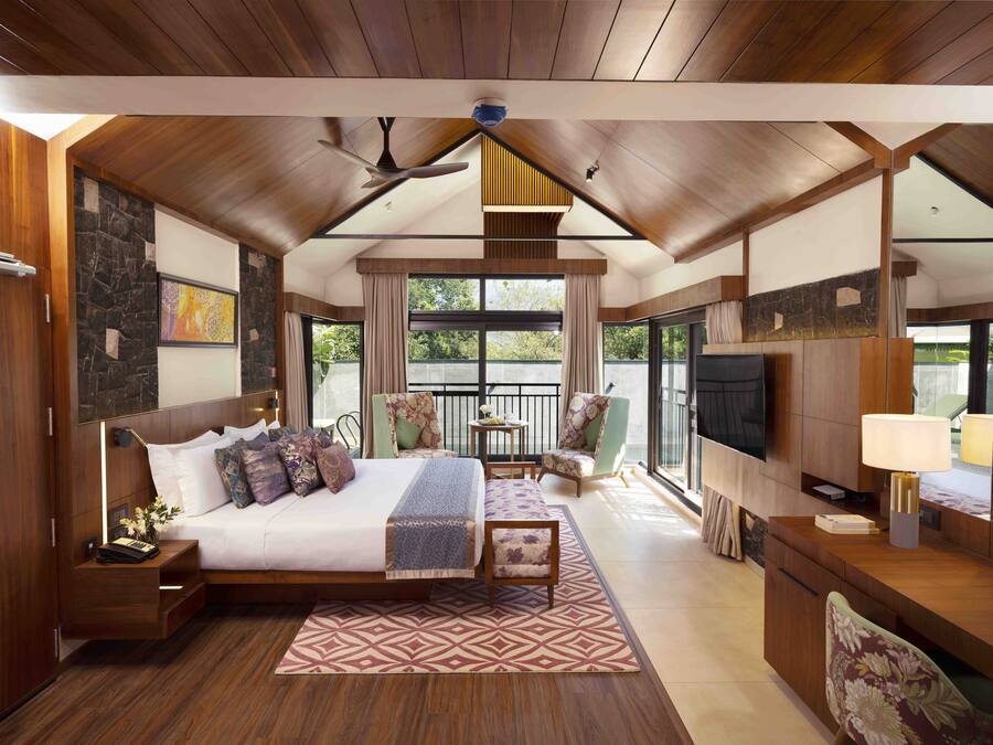 Un dormitorio amplio con una cama grande, televisión, escritorio y balcón con vistas.