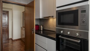 Una cocina moderna con electrodomésticos de acero inoxidable, suelo de madera y un hervidor rojo sobre la encimera.
