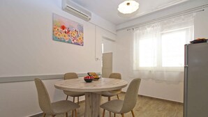 A dining area with a round table, four chairs, a bowl of fruit, and a refrigerator. - Holiday apartment with a/c (Fažana)