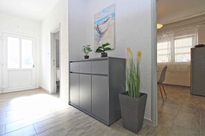 Een moderne keuken met een grijs kastje, een schilderij aan de muur en een potplant.