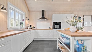 A modern kitchen with white cabinetry, a wooden countertop, and a central island with a vase of flowers.