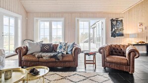 A spacious living room with two leather sofas, a small wooden table, and a large window with a view of the outdoors.