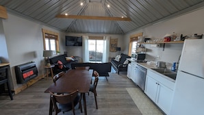 A compact kitchen with a dining area, a sofa, and a TV mounted on the wall.