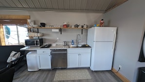 A compact kitchen with a microwave, toaster, sink, and white cabinets.