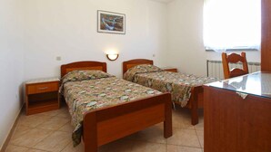 Une petite chambre à coucher avec deux lits en bois, une table de chevet, une table et une chaise.