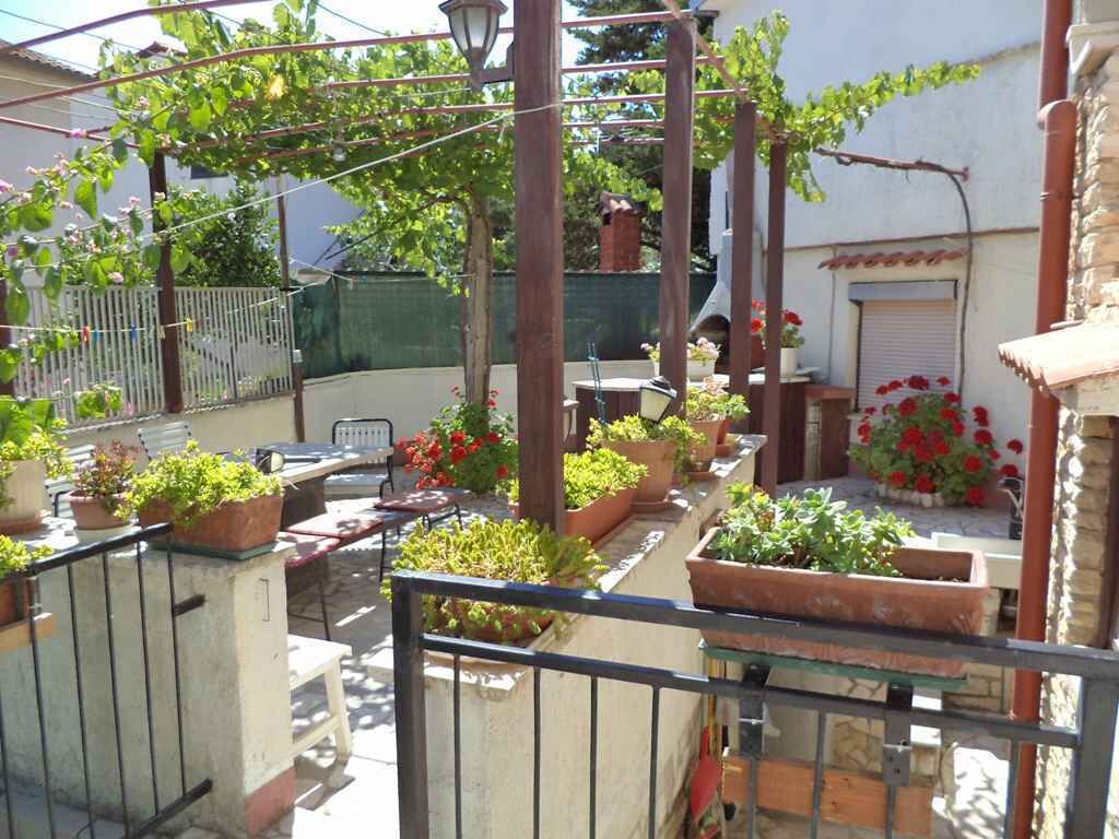Een balkon met bloempotten, een tafel en stoelen.