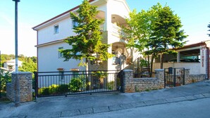Un immeuble de deux étages avec une façade en pierre, un balcon et un garage.