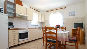 Une cuisine compacte avec un coin repas, comprenant une cuisinière, un four et une petite table avec des chaises.