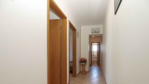 Un couloir étroit avec des portes en bois et un sol carrelé.