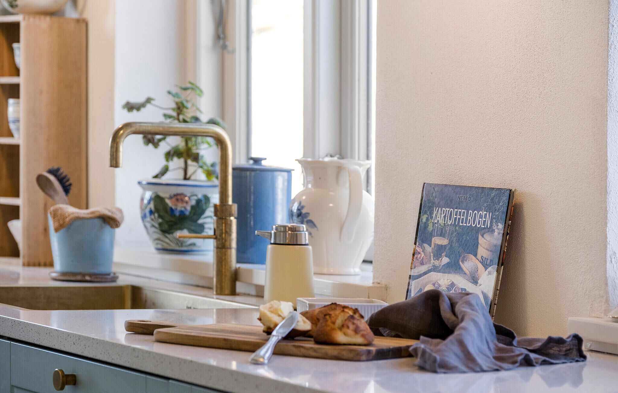 Una encimera de cocina con una cafetera, una tabla de cortar y un plato de comida.