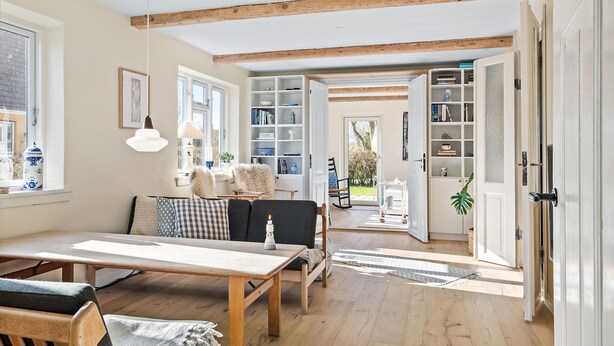 A cozy living room with a wooden table, chairs, and a bookshelf.