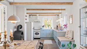 A cozy kitchen with a wooden table, a stove, and a window overlooking a garden.