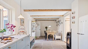A kitchen with a dining area, a fireplace, and a window with plants.