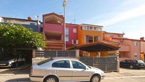 A beige sedan parked on a residential street with colorful houses in the background. - Holiday apartment with air conditioning (Pula)