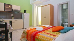 A compact room with a bed, a small kitchenette, a bathroom, and a wardrobe. - Holiday apartment with air conditioning (Pula)