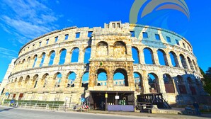 A historic stone amphitheater with multiple arches and a central entrance. - Holiday apartment with air conditioning (Pula)