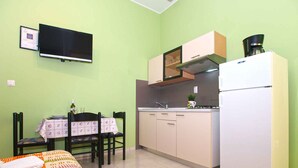 A compact kitchen with a dining area, a flat-screen TV, and a coffee maker. - Holiday apartment with air conditioning (Pula)