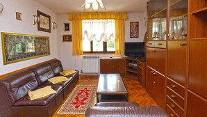Ein Wohnzimmer mit einem braunen Ledersofa, einem Glastisch, einem Holzschrank und einem Fernseher.