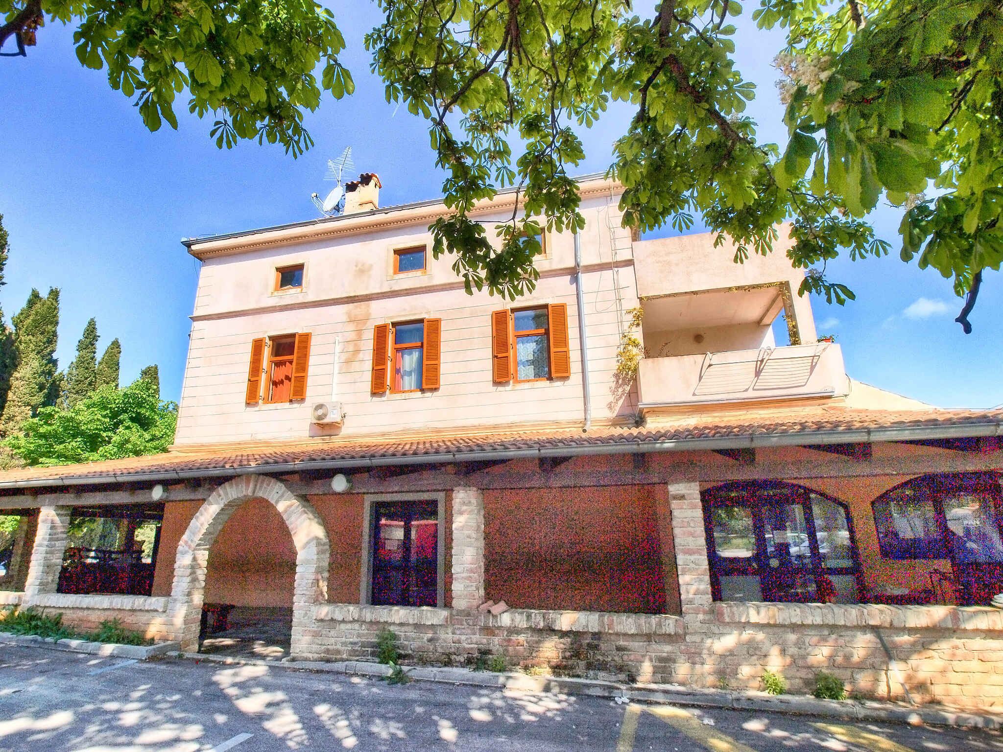 A two-story building with a balcony, arched windows, and a tiled roof.
