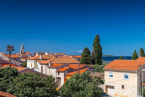 A coastal town with red-tiled roofs, stone buildings, and a clear blue sky.