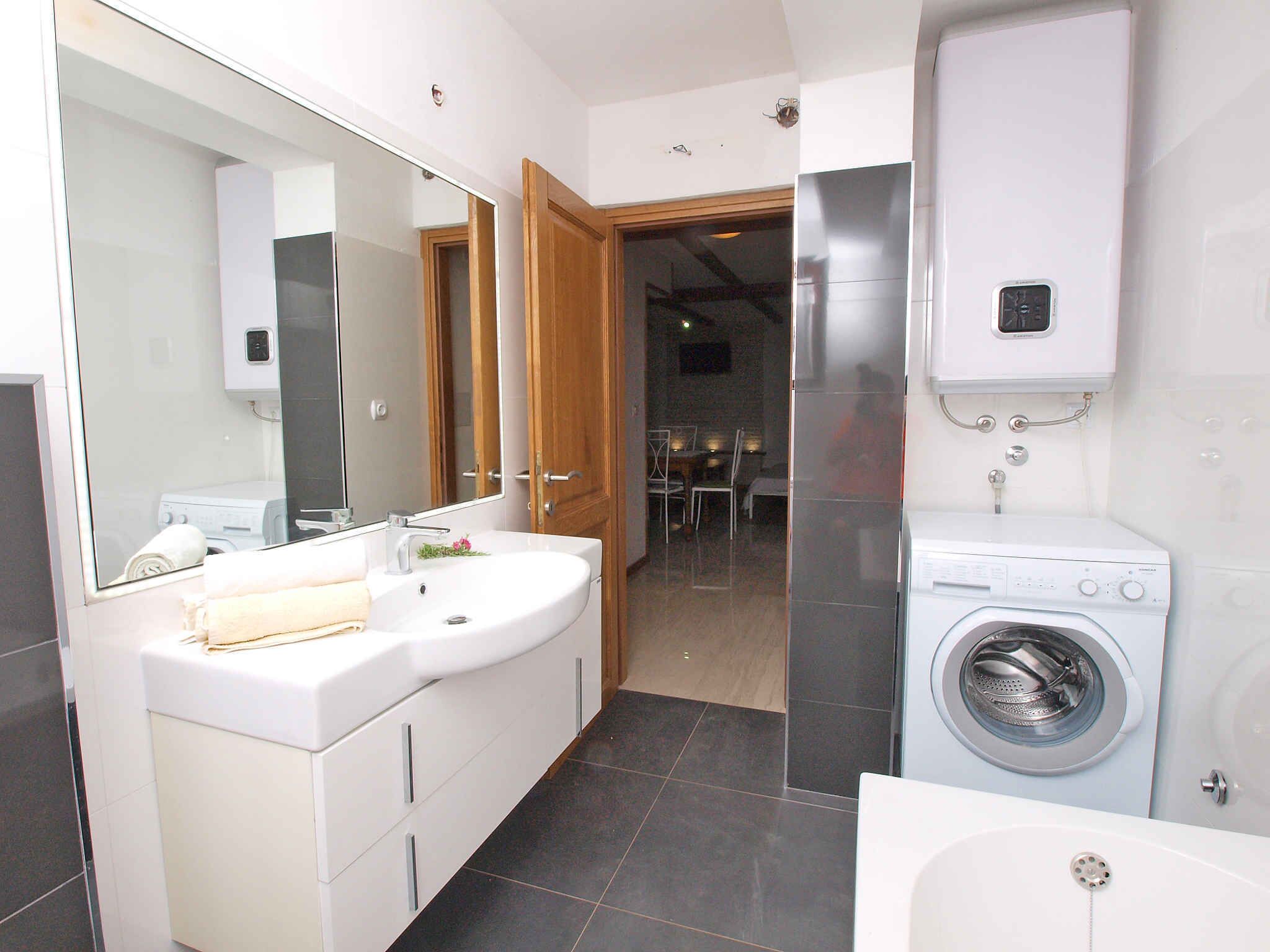 Un baño moderno con un espejo grande, un tocador doble, una lavadora y un inodoro.