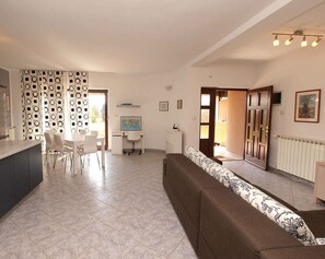 Cozy living area with a dining table, sofa, desk, and kitchenette.