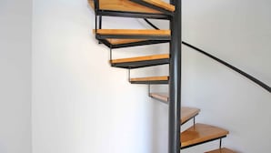 A spiral staircase with wooden steps and a black metal railing.
