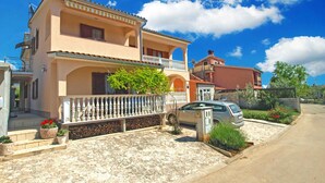 A two-story house with a balcony, a driveway, and a parked car.