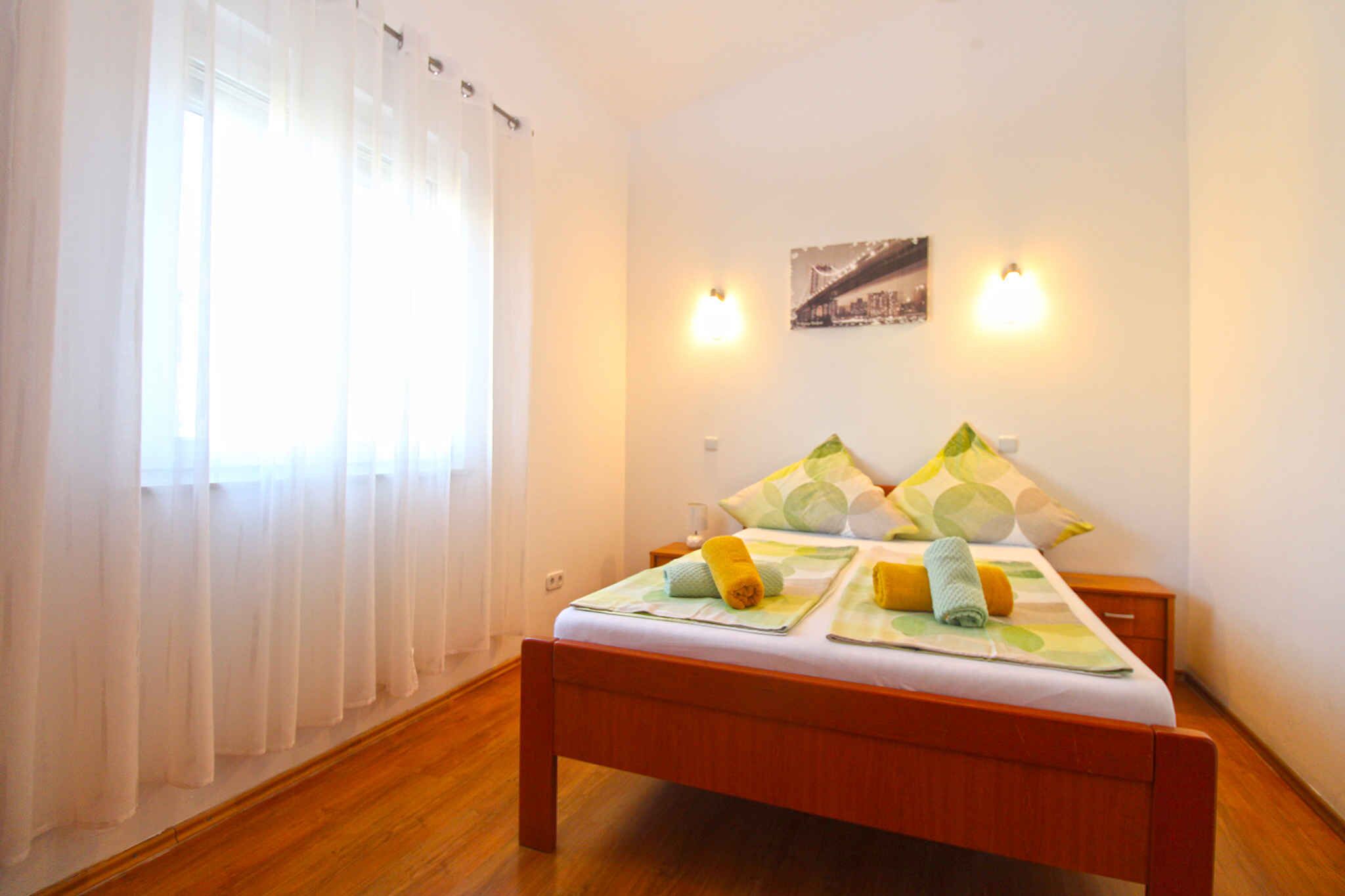 A neatly arranged bedroom with a wooden bed, white curtains, and two wall-mounted lights.