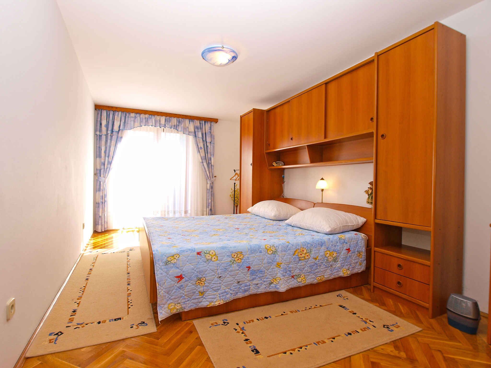 A bedroom with a bed, wooden wardrobe, and a window with curtains.