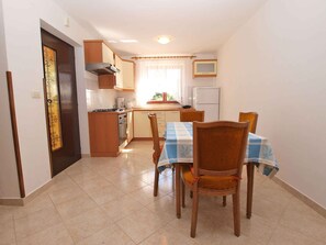 A compact kitchen with a dining area, featuring a stove, oven, and a small refrigerator.