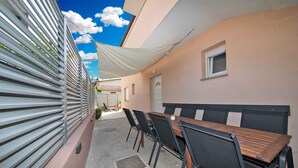 A covered outdoor dining area with a table and chairs, a white awning, and a building with a door and window. - Holiday apartment with air conditioning (Štinjan)