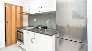 A compact kitchen with a stainless steel refrigerator, a double sink, and a built-in oven.