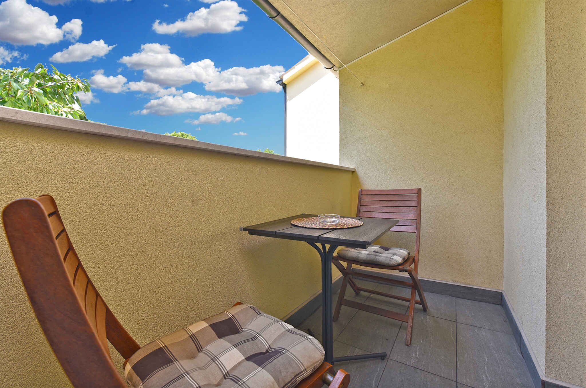 A balcony with a wooden chair and a small table with a placemat and a glass.