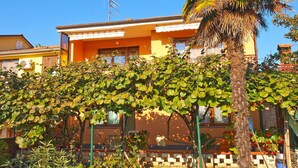 A residential building with a yellow facade, a palm tree, and a well-maintained garden with various plants. - Holiday apartment with air conditioning (Valbandon)